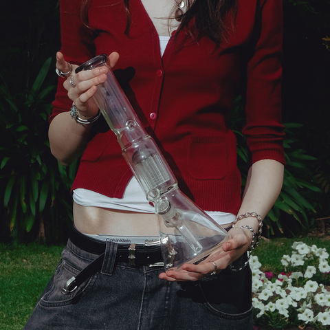 Shotties 40cm Glass Slit Fountain Beaker Bong - Clear Beaker Bong Standing Upright Held by Female Model in flower garden