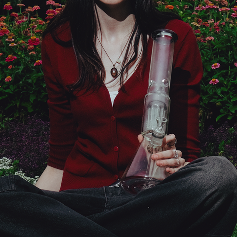 Shotties 40cm Glass Slit Fountain Beaker Bong - Clear Beaker Bong Standing Upright Held by Female Model in flower garden